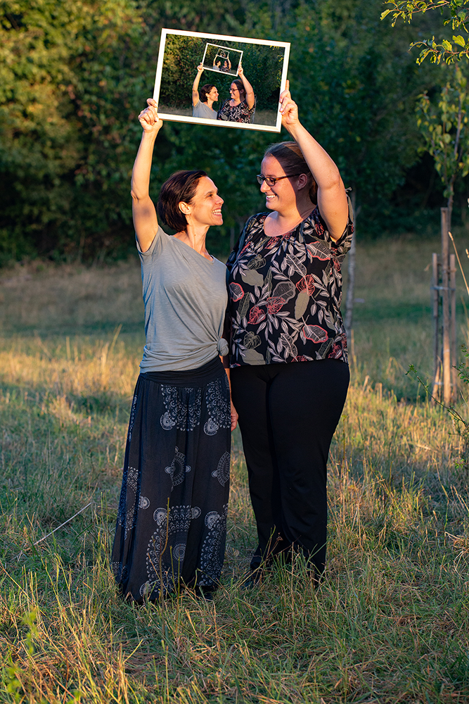 Zwei Frauen halten einen Rahmen in die Luft