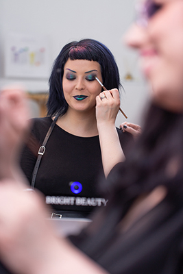 Das Foto zeigt eine Frau, die von Visagistin Bianca geschminkt wird. Das Foto wurde im Studio Beautyversum von Fotografin Heidi Holtel aufgenommen.